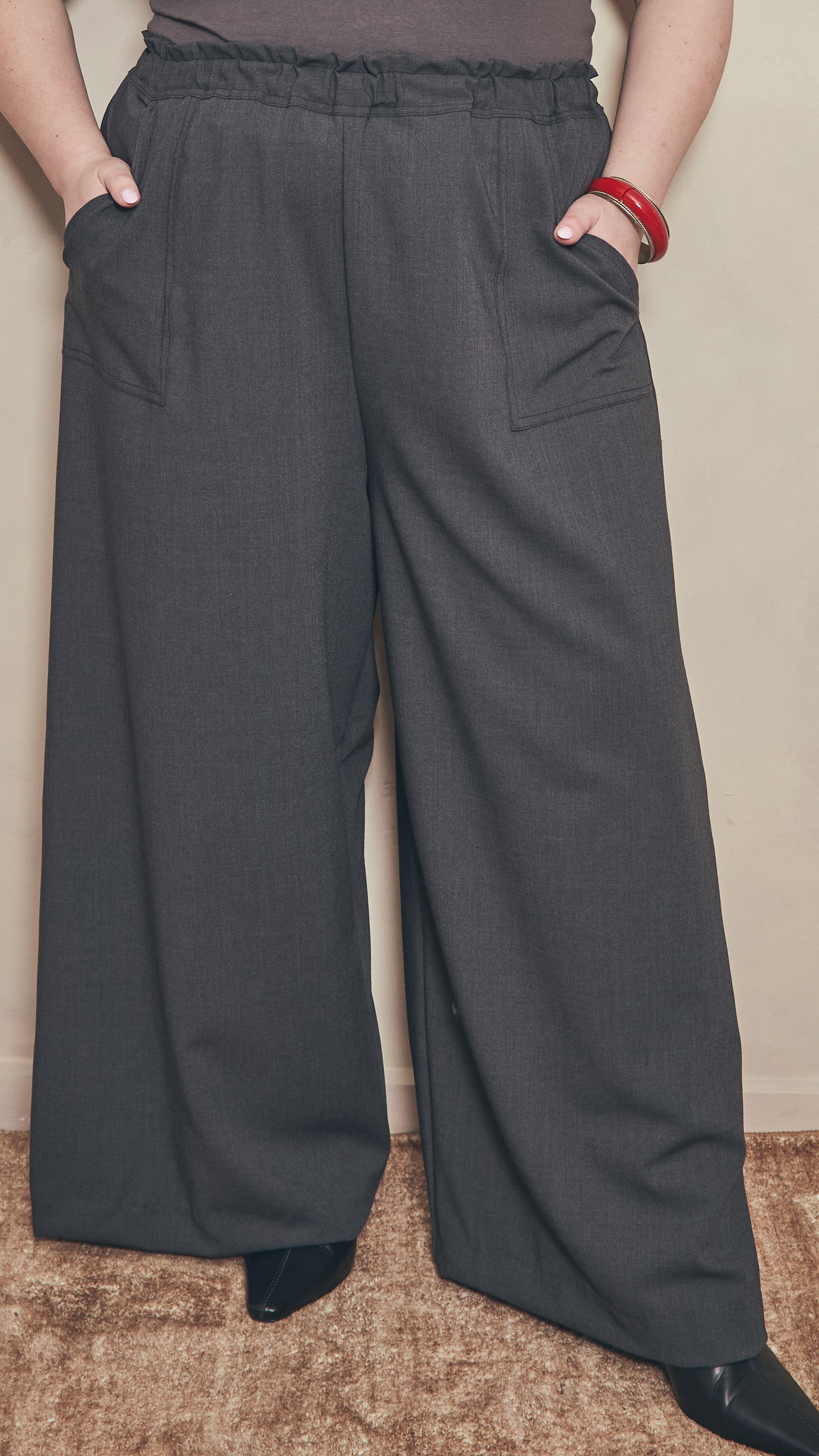 Full length image of model wearing charcoal palazzo pants and black pointed toe shoes 