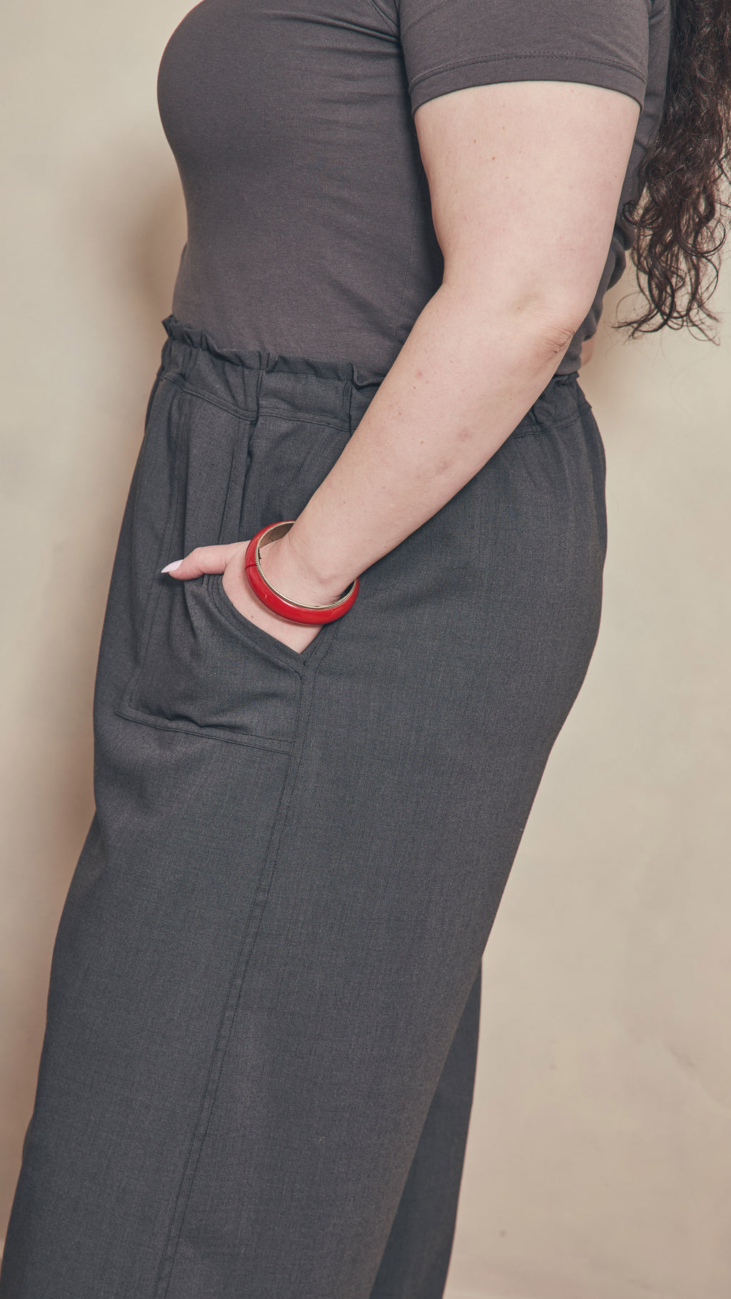 Side view of charcoal pants showing contrast double stitching on the side seam.