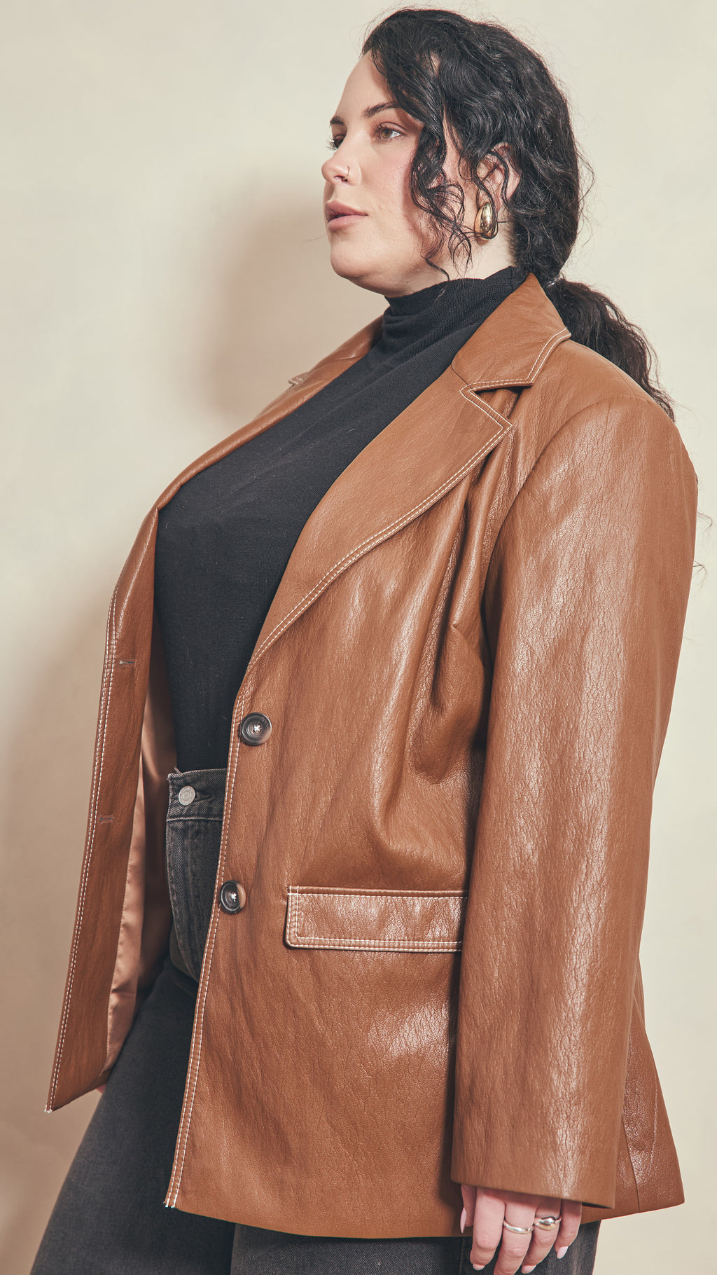 Side front view of model wearing a burnt toffee jacket showing welt pocket detail and all contrast cream stitching