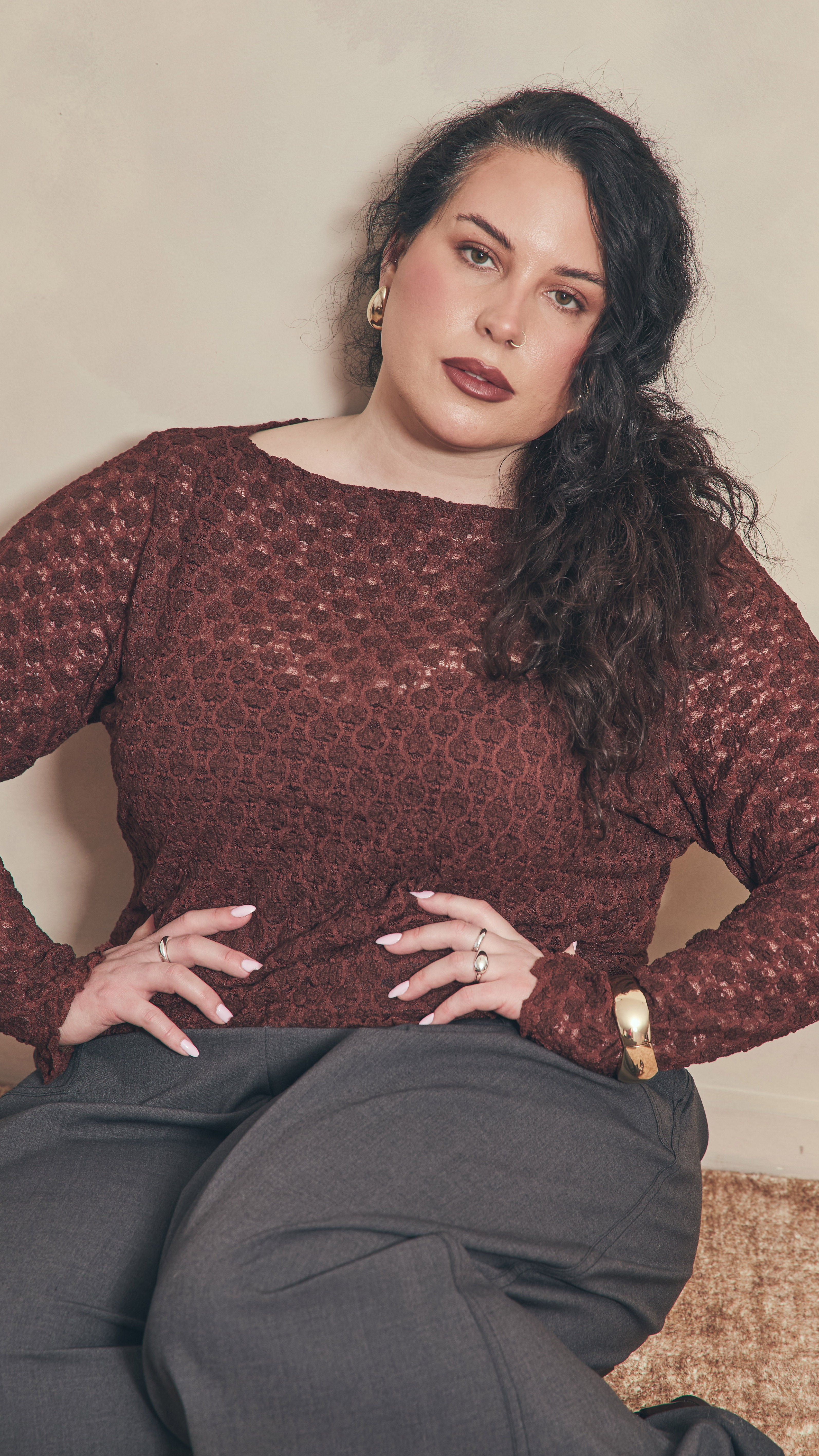 Modal sitting on the floor with her hands on her hips wearing a chocolate lace top